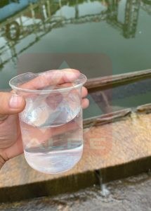 a hand holding a beaker filled with clear water